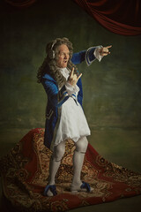 Overjoyed man dressed in richly detailed baroque costume listening music and dance in headphones...