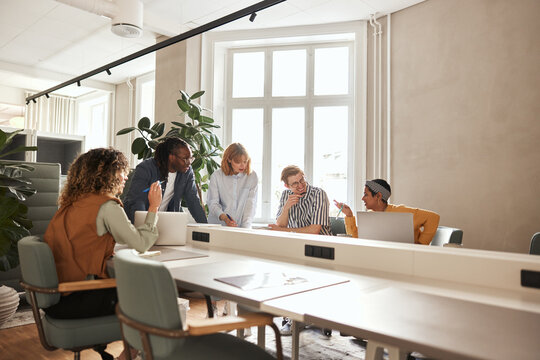 Diverse young business people having a casual meeting, at an office table in an open office space