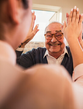 Happy senior man giving high-five to doctor at nursing home