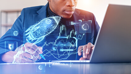 African businessman using laptop, forex hologram with rocket and candlesticks