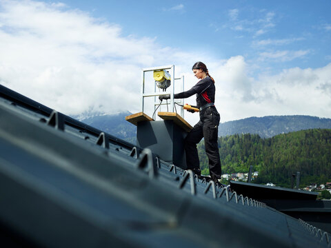 Chimney sweeper repairing chimney standing on rooftop