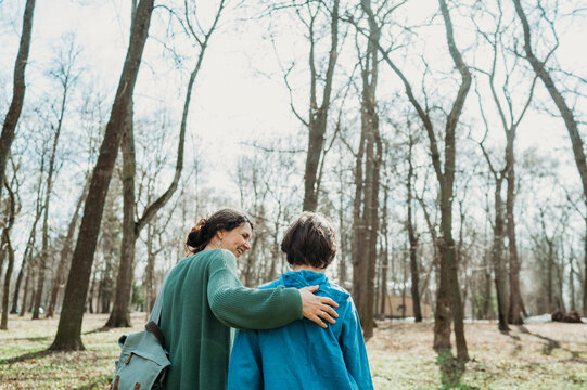 Smiling woman walking with son in front of trees at park