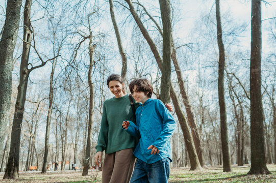 Happy mother and son walking together in front of trees at park