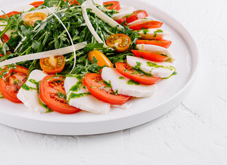Fresh caprese salad with arugula on white plate