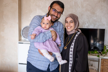 portrait for young family with their first baby holding her and looking at the camera wearing beautiful clothes