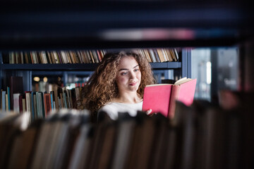 Female student in library, looking for books, preparing for final exam.