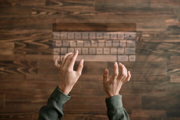 From above view shot of hands of unrecognizable woman typing on virtual keyboard, wooden...