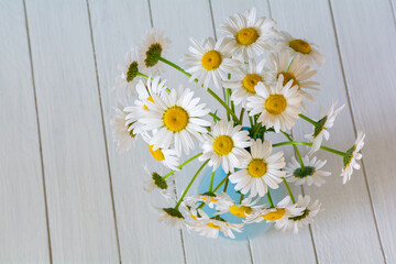 Obraz premium Bouquet of beautiful chamomile flowers in a vase on a white wooden background