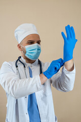 Fototapeta premium Male doctor white uniform putting on protective blue gloves isolated