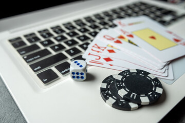 poker playing cards with casino chips on laptop keyboard for online gambling