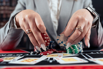 female player takes chips and raises in poker game at casino
