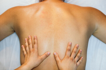 Fototapeta premium top view of a back massage. young woman hands treating male back. physiotherapist