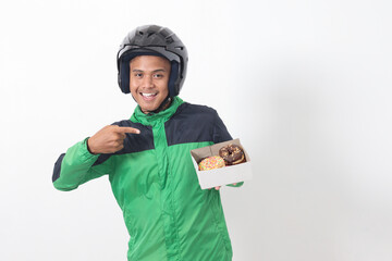 Portrait of Asian online taxi driver wearing green jacket and helmet holding a box of donuts, delivering to customer. Isolated image on white background