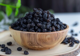 Black raisins in wooden bowl.
