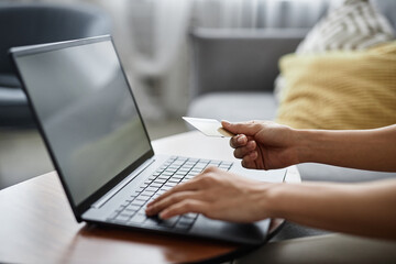 Hands of unrecognizable woman holding credit card paying for goods in online shop on laptop, copy...