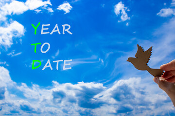 YTD year to date symbol. Concept words YTD year to date on beautiful blue sky clouds background....