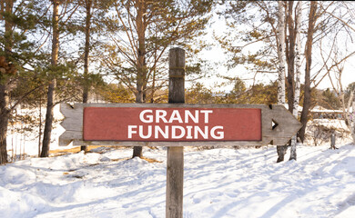 Grant funding symbol. Concept words Grant funding on beautiful wooden road sign. Beautiful forest...