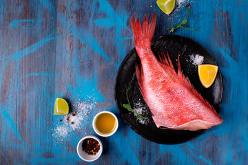 Beaked redfish or perch prepared for cooking a meal with other ingredients around on the blue...