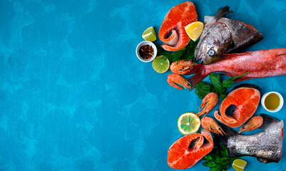 Fresh seafood assortment on blue background. Trout steaks, beaked redfish and shrimps. Cooking...
