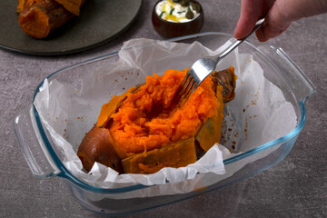 Cooking baked stuffed sweet potato. Scraping and stirring the baked pulp with the fork to add the...