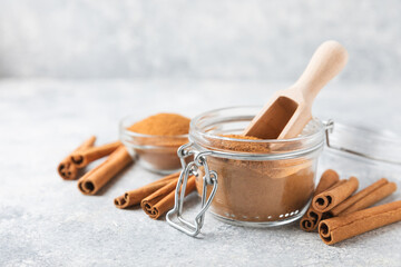 Cinnamon powder in a bowl on a textured wooden background. Spicy spice for baking, desserts and drinks. Fragrant ground cinnamon. Cinnamon stick. Place for text. Copy space.