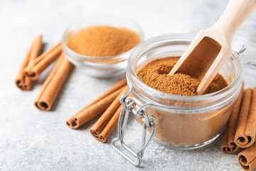 Cinnamon powder in a bowl on a textured wooden background. Spicy spice for baking, desserts and drinks. Fragrant ground cinnamon. Cinnamon stick. Place for text. Copy space.