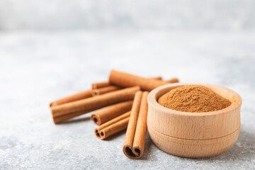 Cinnamon powder in a bowl on a textured wooden background. Spicy spice for baking, desserts and...