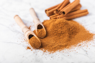 Cinnamon powder in a bowl on a textured wooden background. Spicy spice for baking, desserts and drinks. Fragrant ground cinnamon. Cinnamon stick. Place for text. Copy space.