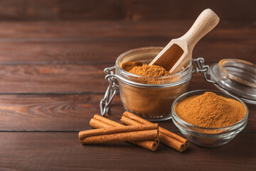 Cinnamon powder in a bowl on a textured wooden background. Spicy spice for baking, desserts and...