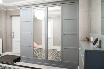 Spacious hallway in the apartment with gray walls, wardrobe and large mirrors
