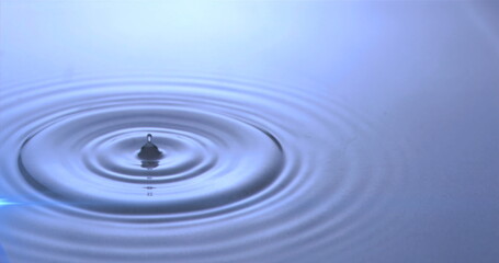 Image of water drops dropping into blue water with glowing light