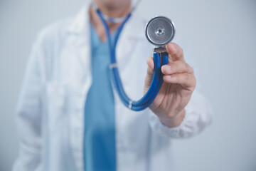 Senior doctor wearing white coat standing holding stethoscope in hands. Older male physician...