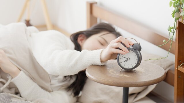 目覚まし時計を止める女性