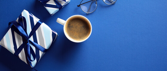 Stylish flat lay with coffee, eyeglasses and gift box in blue hues, perfect for fathers day theme.