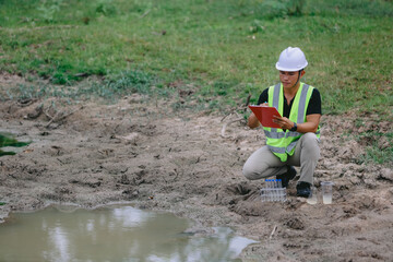 Asian man environment researcher holds tube of sample water to inspect from the lake. Concept, explore, analysis water quality from natural source. Ecology field research