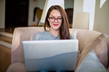 Confident woman sitting at home and using her laptop for work