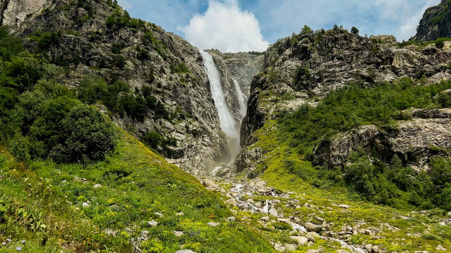 Majestic mountain waterfall cascading through rocky terrain surrounded by lush greenery, ideal for nature, travel themes, and International Mountain Day