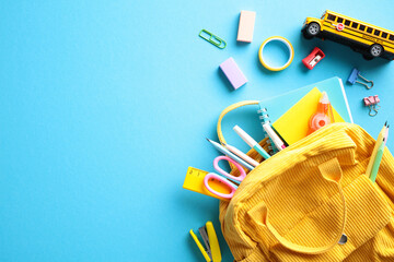 Yellow backpack overflowing with school essentials such as pencils, scissors, and multicolored...