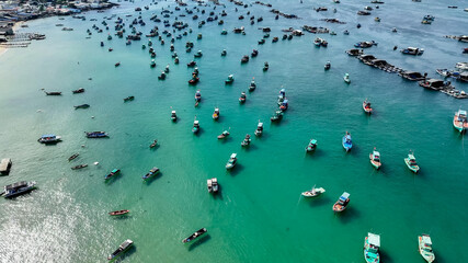 Ariel view of a bustling fishing village with traditional boats floating on a turquoise sea, ideal for travel and cultural diversity themes