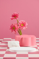 Creative design template of gerbera flower theme in pink tones, white blank tray placed in front with an empty flower shaped pedestal in back. Copy space for text, front view