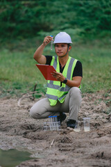 Asian man environment researcher holds tube of sample water to inspect from the lake. Concept, explore, analysis water quality from natural source. Ecology field research