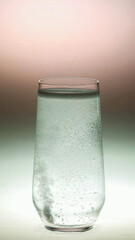 Glass of sparkling water with bubbles on a gradient background, ideal for health and wellness,...