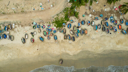 Aerial view of colorful fishing boats on a sandy beach, illustrating coastal life and maritime...