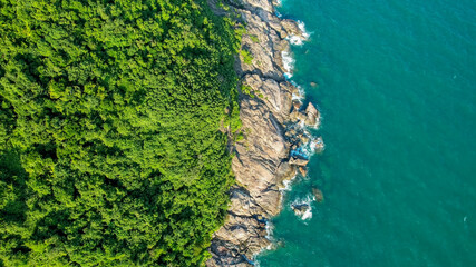 Aerial view of a lush green coastline meeting turquoise waters, ideal for environmental, travel...