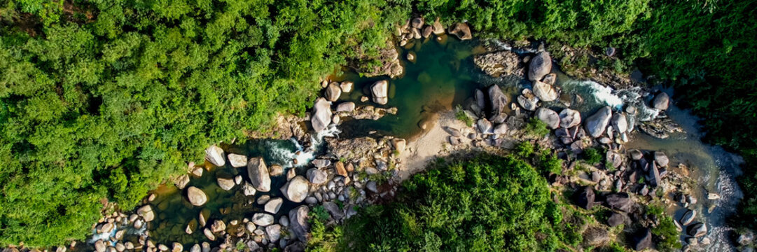 Aerial view of a serene rocky riverbed amidst lush greenery, perfect for themes of nature conservation, Earth Day, and tranquil outdoor landscapes