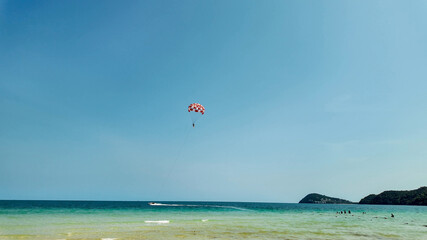 Vibrant parasailing adventure over serene tropical beach waters, ideal for travel and summer...