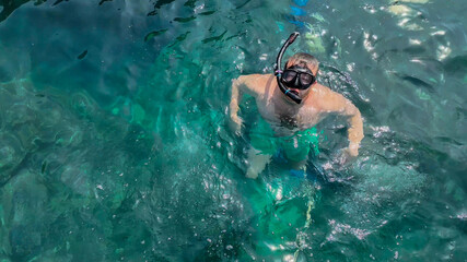Caucasian male snorkeler floating in clear turquoise waters, summer vacation concept, related to World Oceans Day and beach tourism