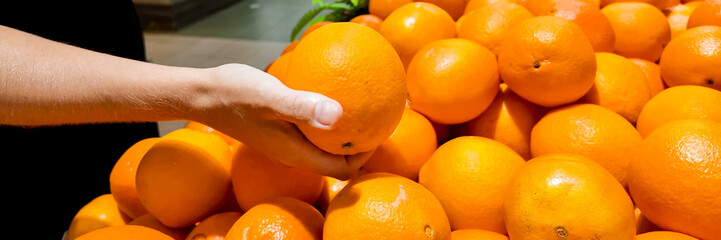 Person selecting fresh oranges at a supermarket produce section, conceptually linked to healthy lifestyle and nutrition, suitable for grocery shopping and citrus harvest themes