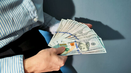 Person holding a fan of US dollars, symbolizing wealth and finance, suitable for tax season and...