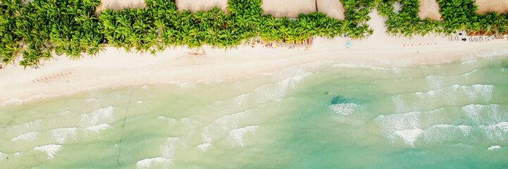 Aerial view of a serene tropical beach with sun loungers and palm trees, ideal for travel and...